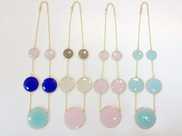 An arrangement of Graduated Quartz Necklaces with circular pastel-colored pendants displayed on a white background.