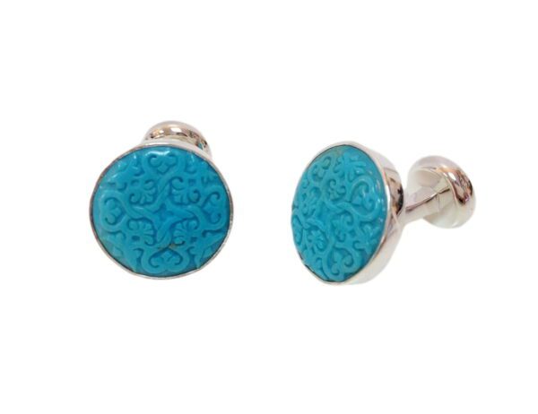 A pair of blue cufflinks with a pattern on them.