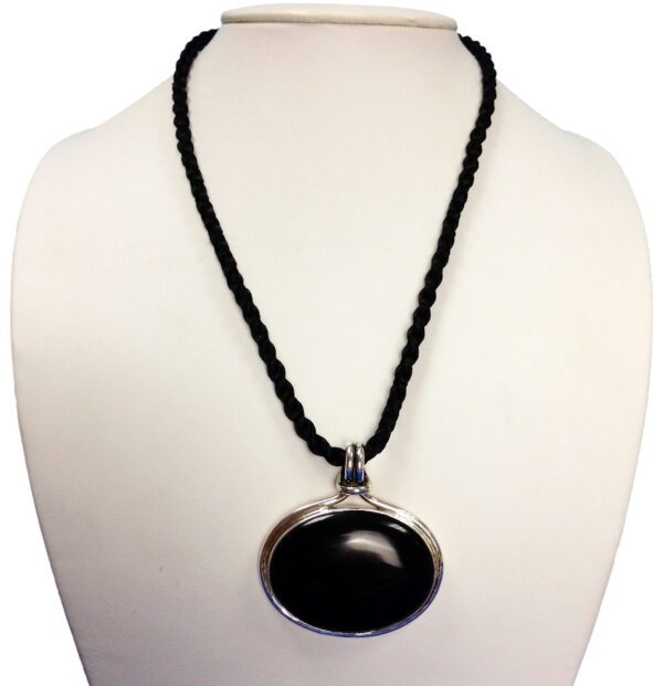 A black stone is on a white necklace.