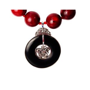 A necklace with red beads and a black pendant.