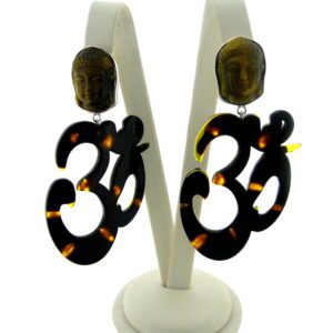 A pair of earrings with Buddha head studs and dangling OM Resin Earrings, displayed on a white stand against a light background.