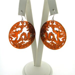 A pair of orange earrings sitting on top of a white stand.