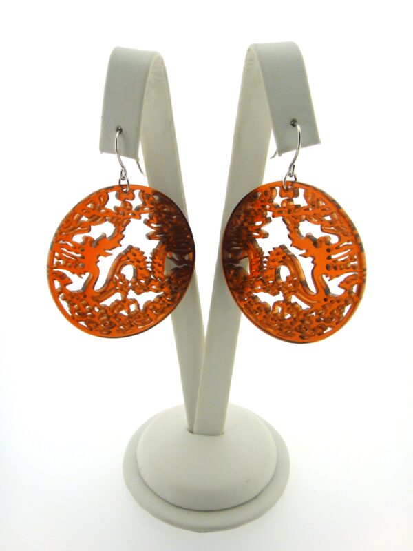 A pair of orange earrings sitting on top of a white stand.