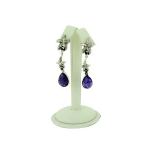 A pair of earrings with purple stones hanging from them.