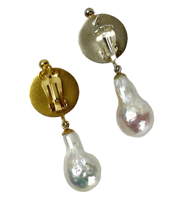 A pair of earrings with pearls hanging from them.