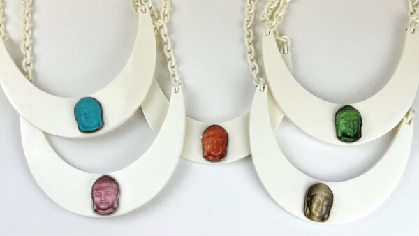 Four Buddha Resin Bib Necklaces with white crescent-shaped pendants and colorful Buddha head beads displayed on a white background.
