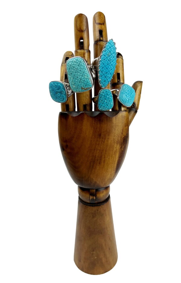 A wooden hand with blue stones on it.