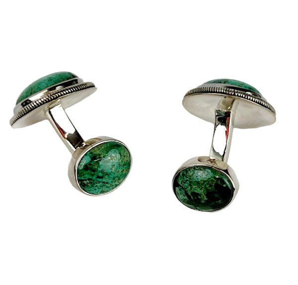 A pair of green cufflinks with silver rim.