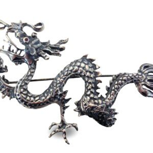 A silver dragon brooch is shown on a white background.