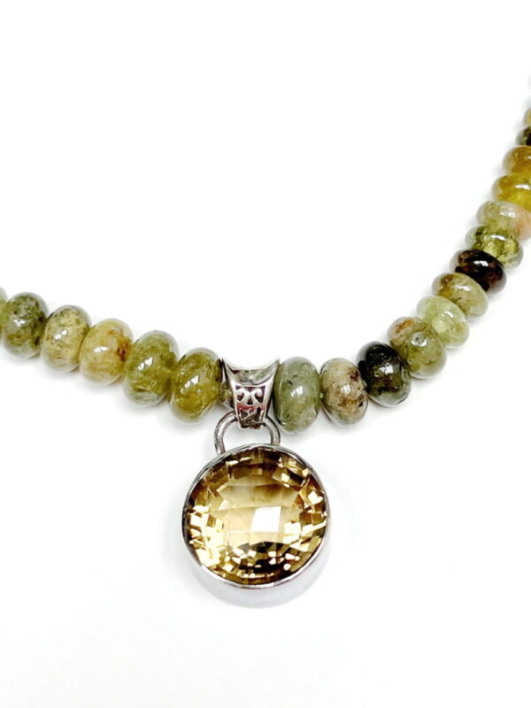 A necklace with a yellow stone and green beads.