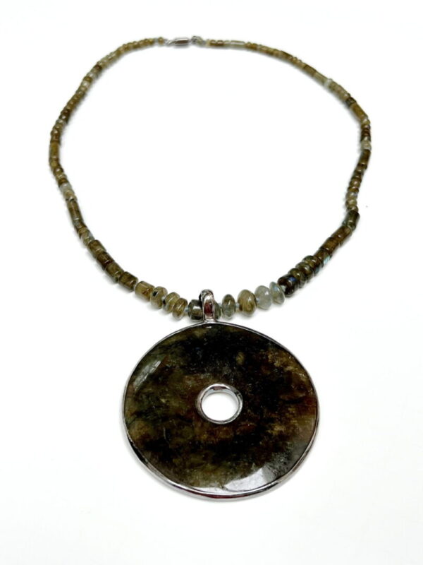 A necklace with a large round pendant and green beads.