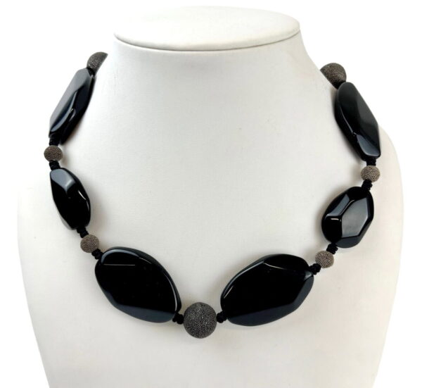 A necklace of black and brown beads on a white bust.