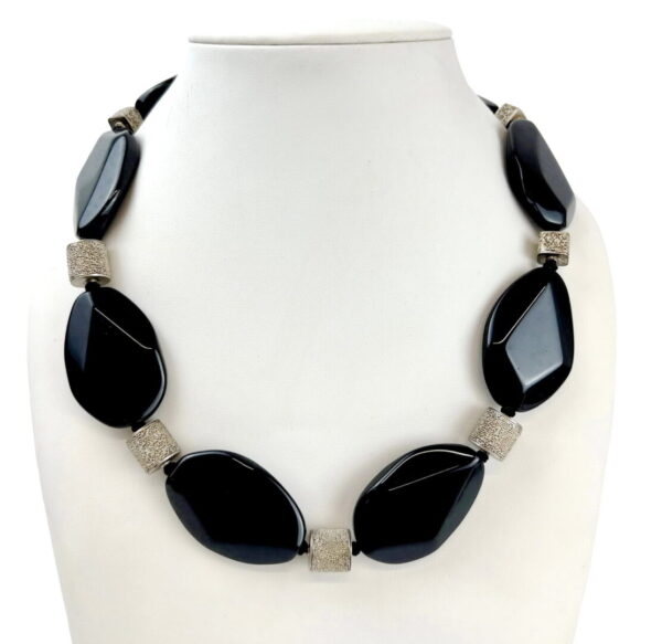 A black and white necklace is sitting on the neck of a woman.