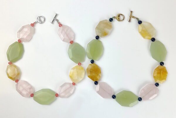 Two necklaces of different colors and shapes on a white surface.