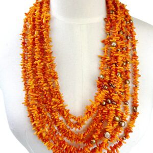 A necklace of orange beads is displayed on the bust.
