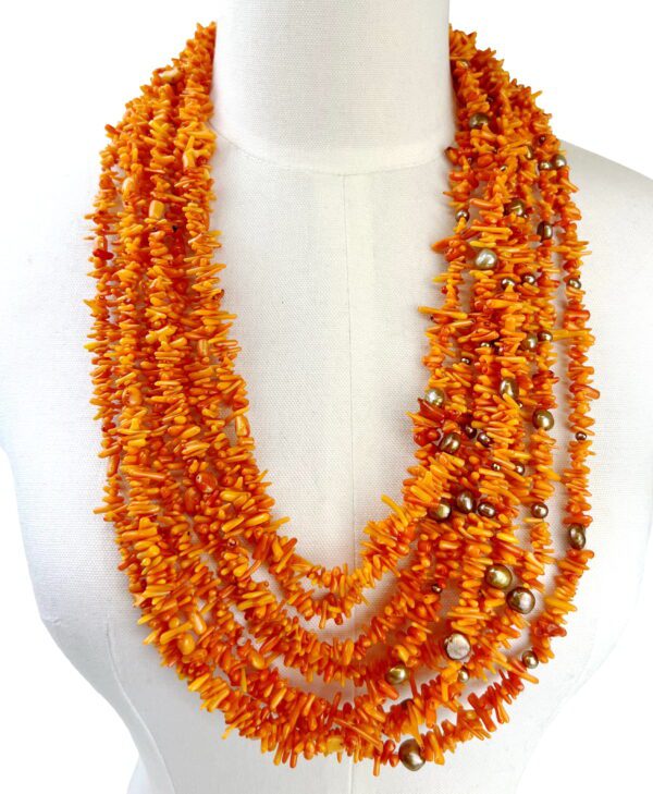 A necklace of orange beads is displayed on the bust.