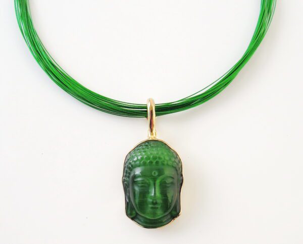 A green jade Buddha pendant hanging on a green multi-strand necklace against a white background.