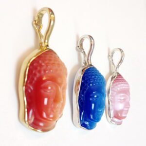 A set of three different colored buddha head shaped pendants.