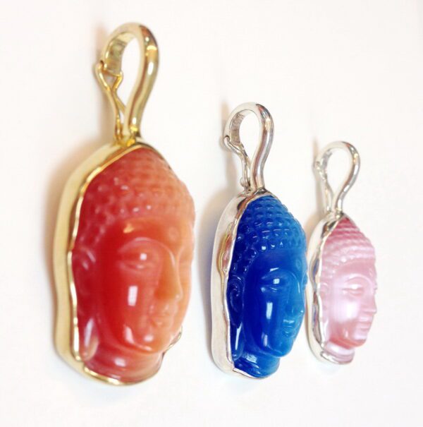 A set of three different colored buddha head shaped pendants.