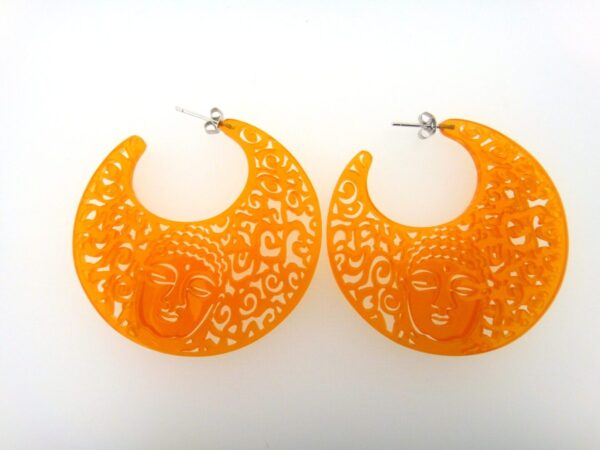 A pair of orange earrings with faces on them.