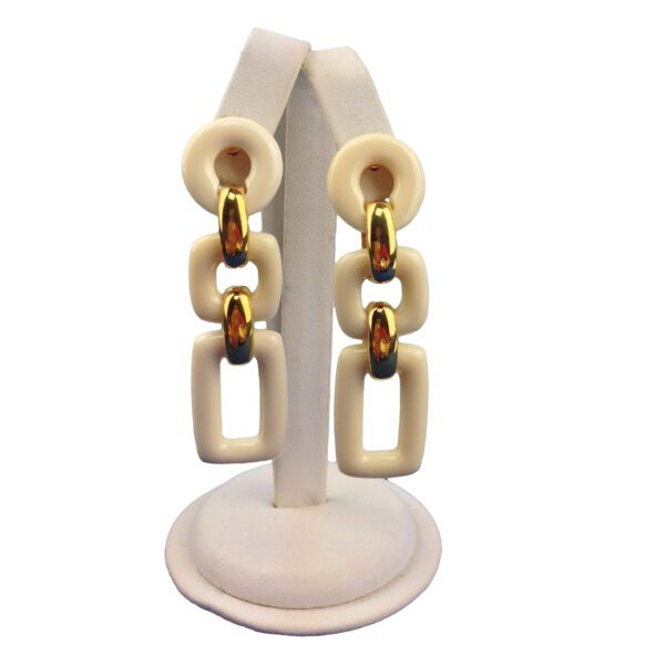 A display stand holding four pairs of Geometric 3 Tier Resin Earrings with amber-colored insets, isolated on a white background.