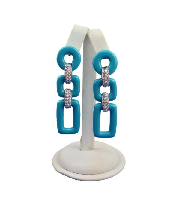 A jewelry stand displaying a pair of Geometric 3 Tier Resin Earrings in turquoise and silver glitter on a white background.