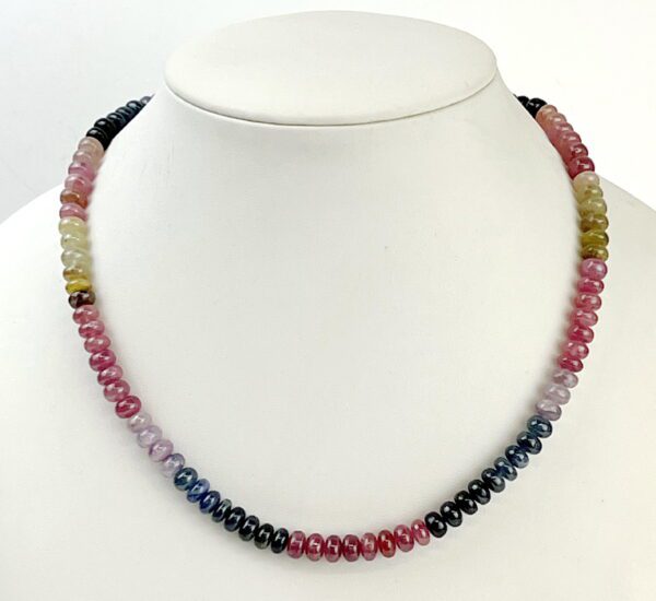 A necklace of multi colored tourmaline beads on a white background