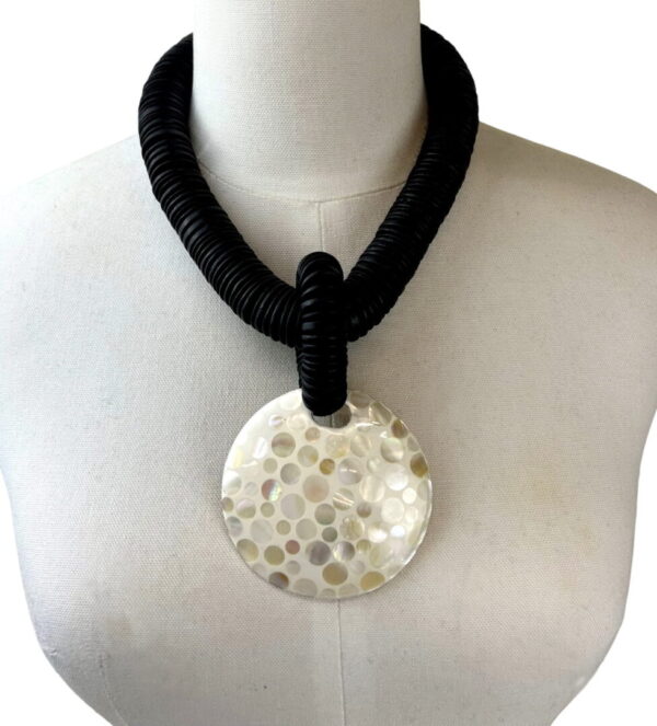 A necklace with a large white disc on it