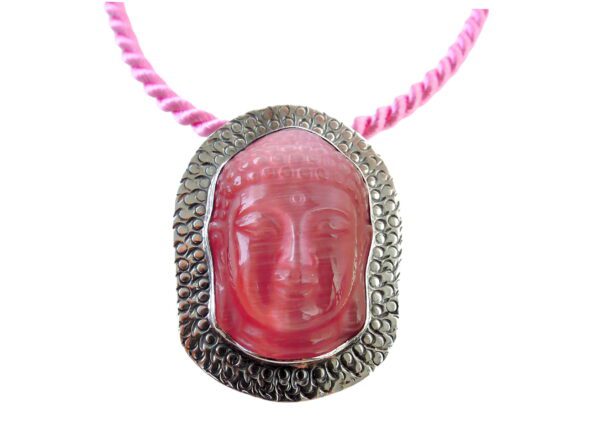 Buddha Silhouette Brooch / Pendant depicting a serene face, set in a decorative metal frame, suspended on a pink braided cord.