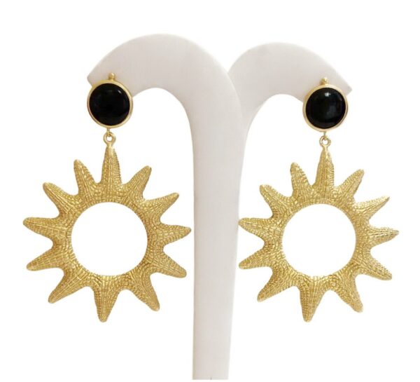 A pair of earrings with sun design and black stone.