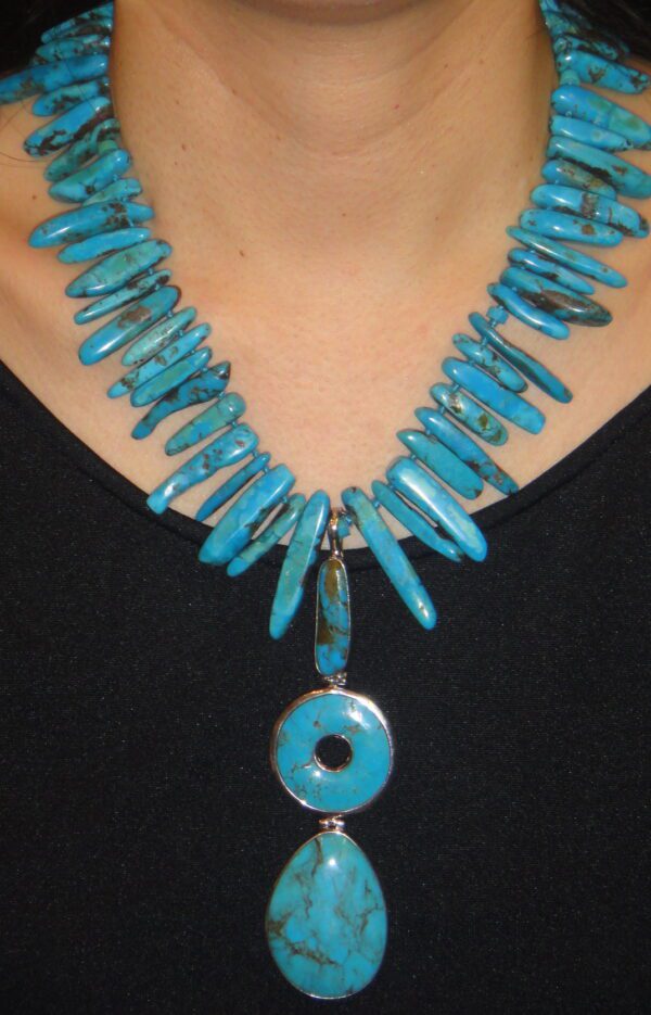 A woman wearing a necklace with turquoise beads.