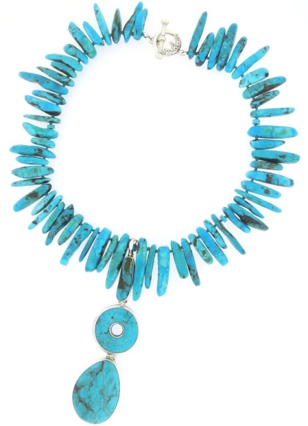 A turquoise necklace with a large pendant hanging from the end of it.