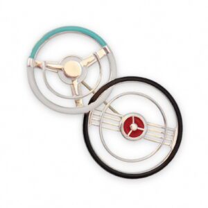 Two Double Steering Wheel Brooches, one with teal and silver accents, the other with black and red, both on a white background.