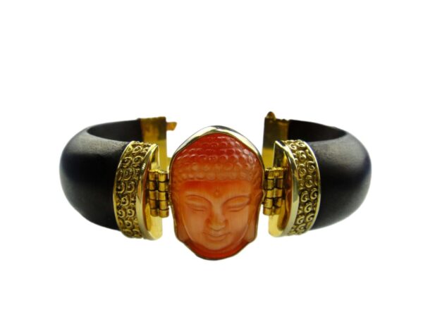 A bracelet with an orange buddha face on it.
