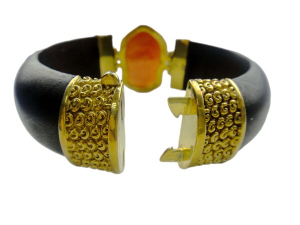 A black and gold bracelet with an orange stone.