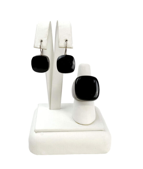 A white earring and ring set with black stones.