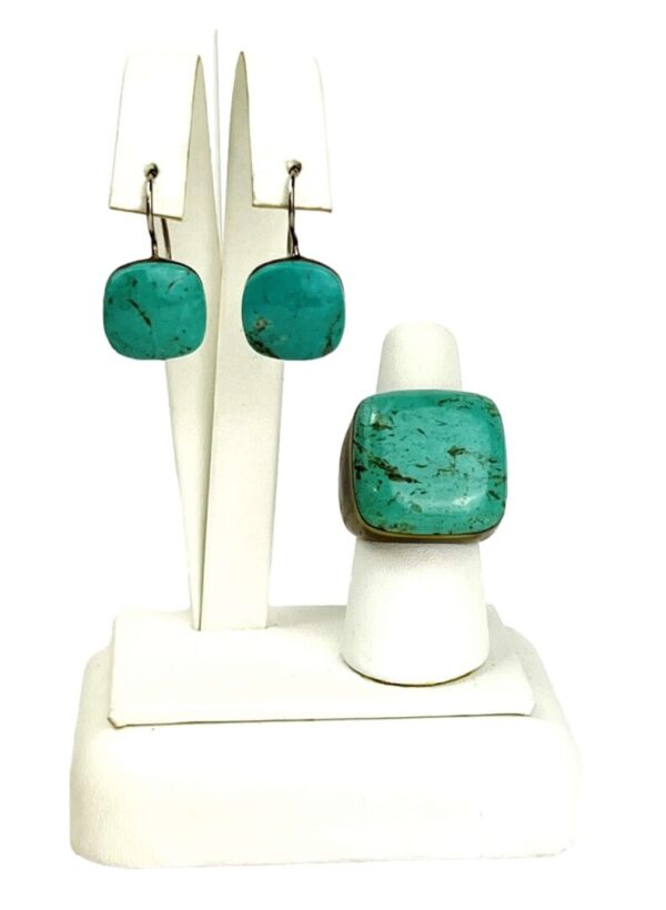 A white stand with a ring and earrings on it