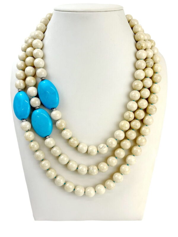 A necklace with three strands of beads and turquoise stones.