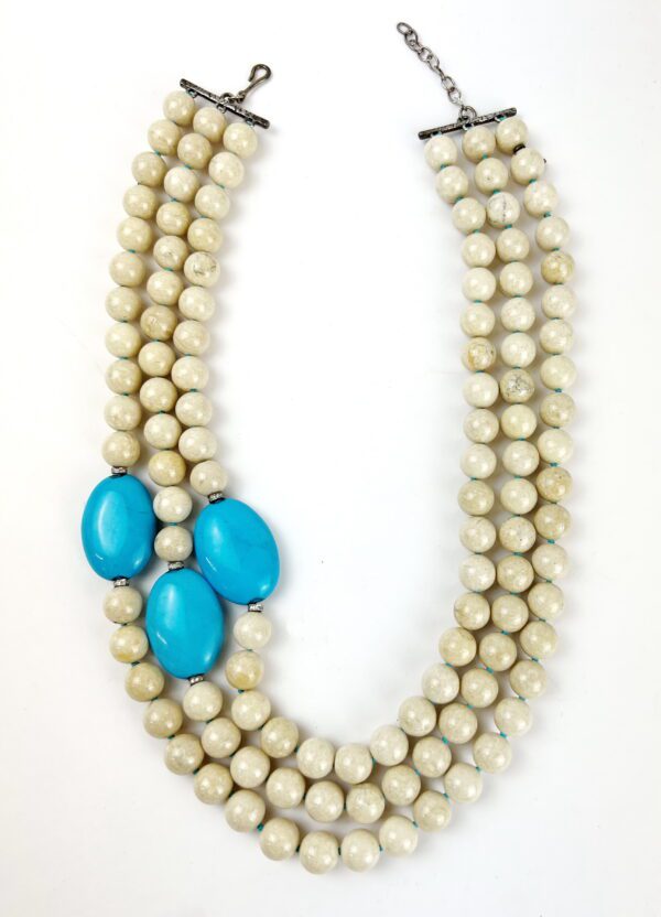 A necklace with three strands of beads and turquoise stones.