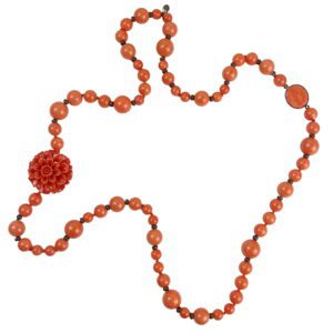 A long necklace with orange beads and a flower.