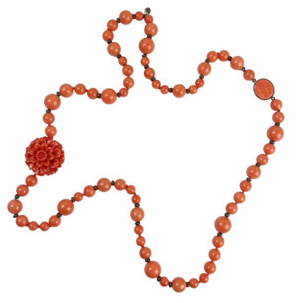 A long necklace with orange beads and a flower.