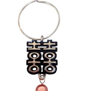 A keychain with a chinese symbol and a pink bead.