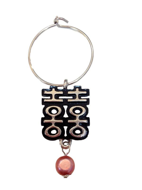 A keychain with a chinese symbol and a pink bead.