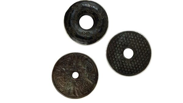 Three black coins are sitting on a table.