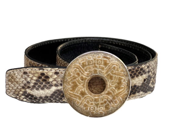 A snake skin belt with a round button on it.