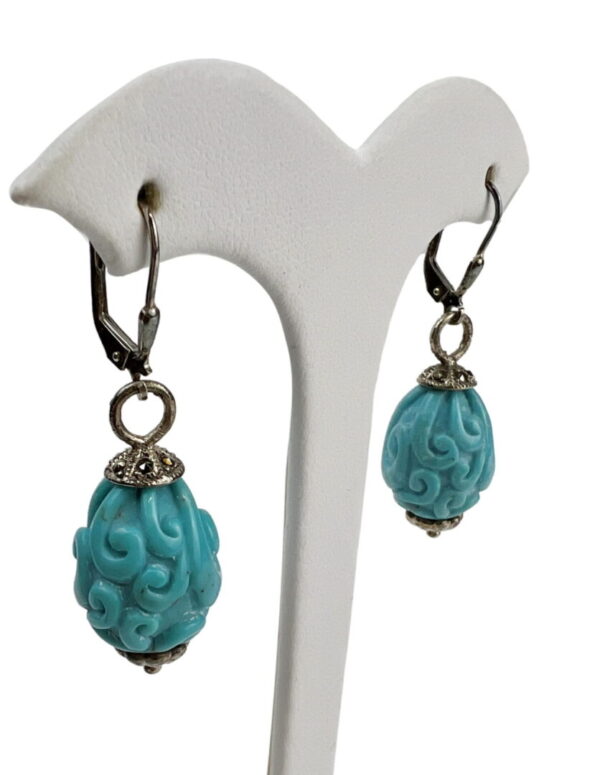 A pair of earrings with blue beads on them.