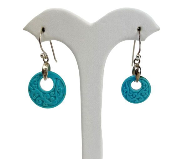 A pair of earrings sitting on top of a white stand.