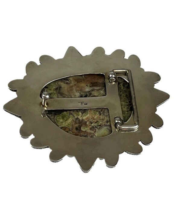 A silver belt buckle with a picture of a flower.