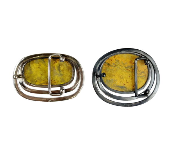 A pair of metal buckles with yellow stones.