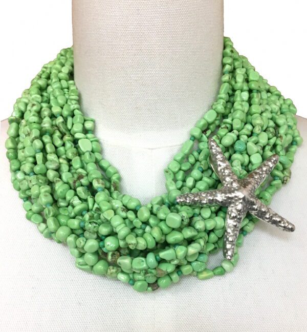 A green necklace with a silver starfish on it.